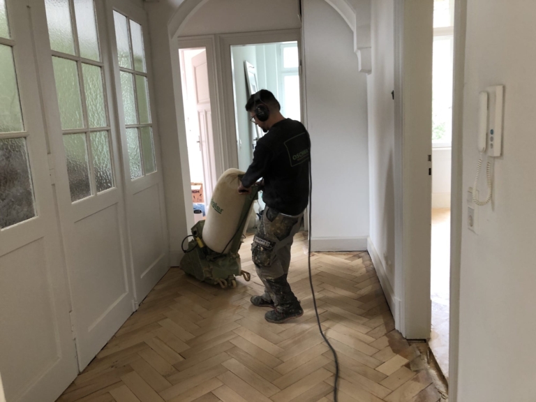 OSCHWALD Bodenleger schleift Fischgrätparkett im Flur einer Altbauwohnung in Freiburg
