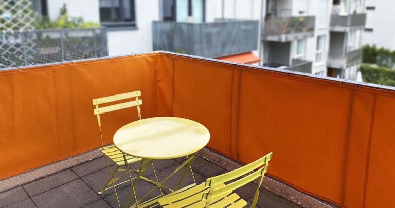 Orangefarbenes Balkontuch als Sichtschutz an der Balkonbrüstung