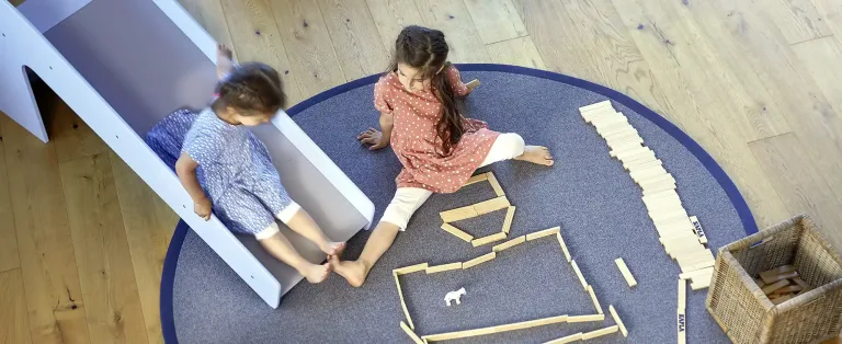 Kinder spielen auf einem runden Teppich im Kinderzimmer